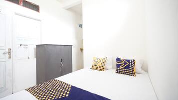 Quarto de hotel com uma cama, um guarda-roupa e uma porta.