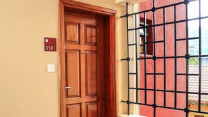 A wooden door with a number plate, a window with a metal grid, and a tiled floor. - South Suites Studios (Nairobi)