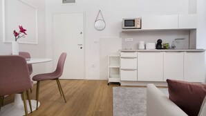 Un soggiorno moderno e minimalista con angolo cottura, zona pranzo e un’accogliente area relax.