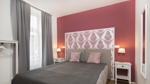 Una camera da letto con un letto grande, due comodini con lampade, un armadio e una testiera decorata.