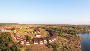 Un resort con disposición curvilínea de cabañas, piscina y vista al lago.