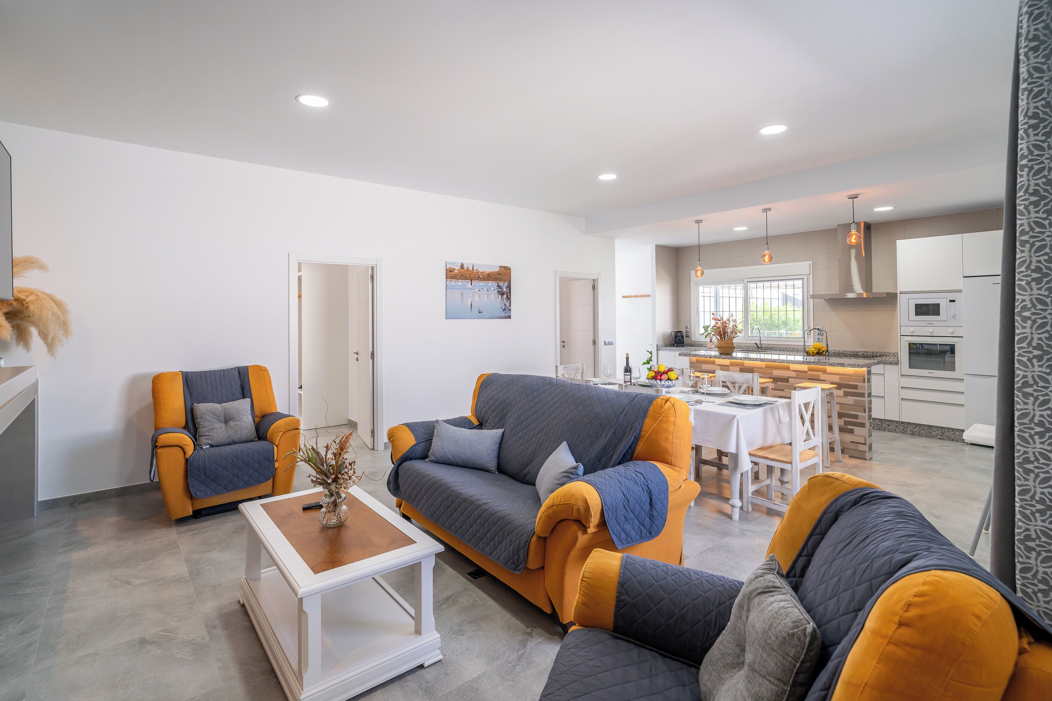 A modern living room with a sofa, armchairs, and a dining area.