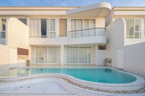 A modern two-story building with a swimming pool, large windows, and a balcony. - Aadhitiya Private Pool Villas (Tha Mai)