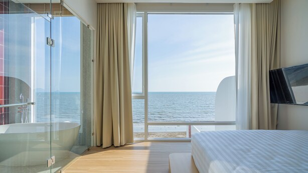A hotel room with a large window, a bathtub, and a bed. - Aadhitiya Private Pool Villas (Tha Mai)