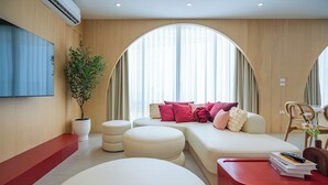 A modern living room with a sofa, ottomans, a red table, and a potted plant. - Aadhitiya Private Pool Villas (Tha Mai)
