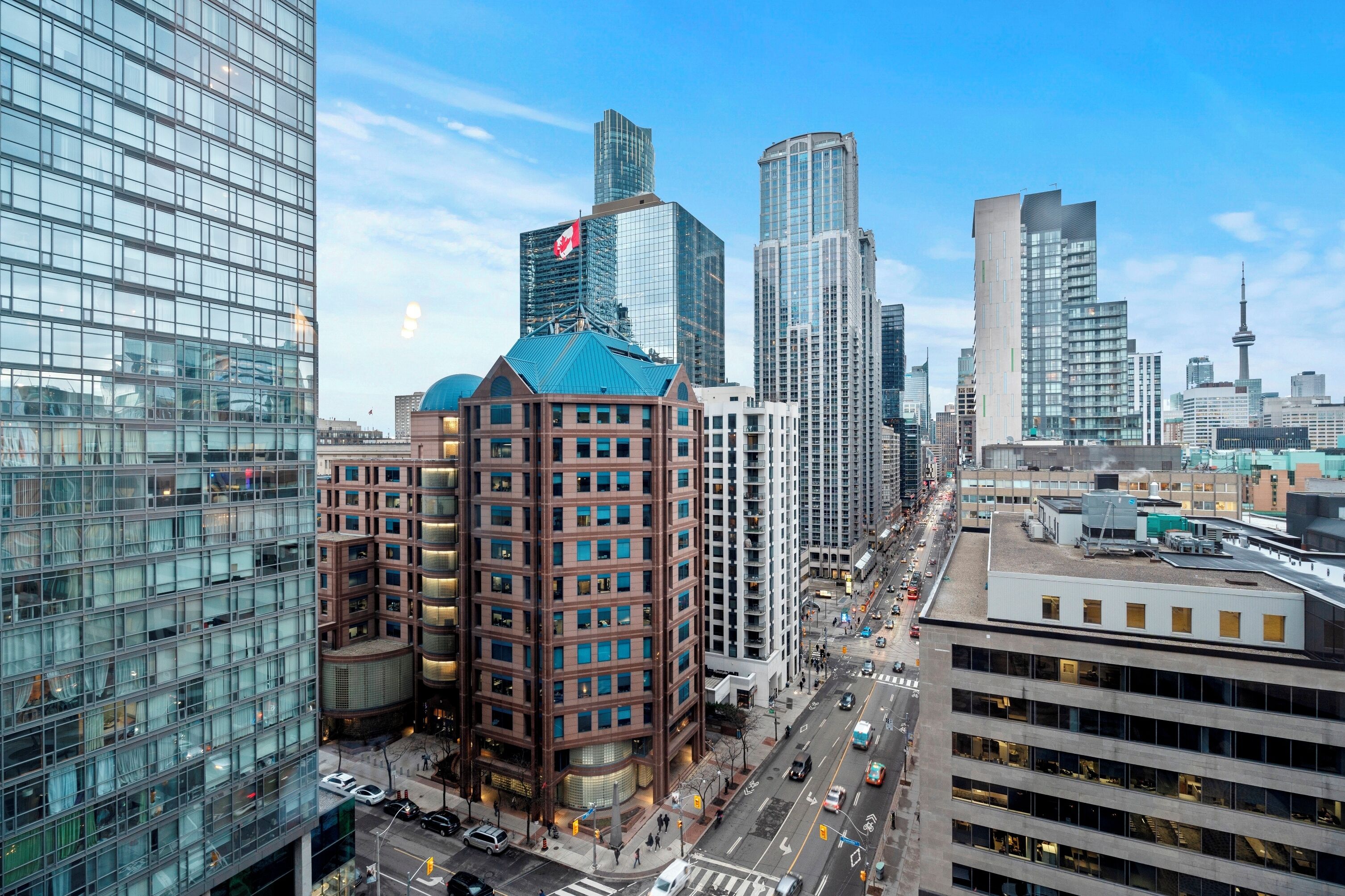 Une vue urbaine avec des immeubles modernes de grande hauteur, un bâtiment remarquable avec un toit rouge et un ciel dégagé.