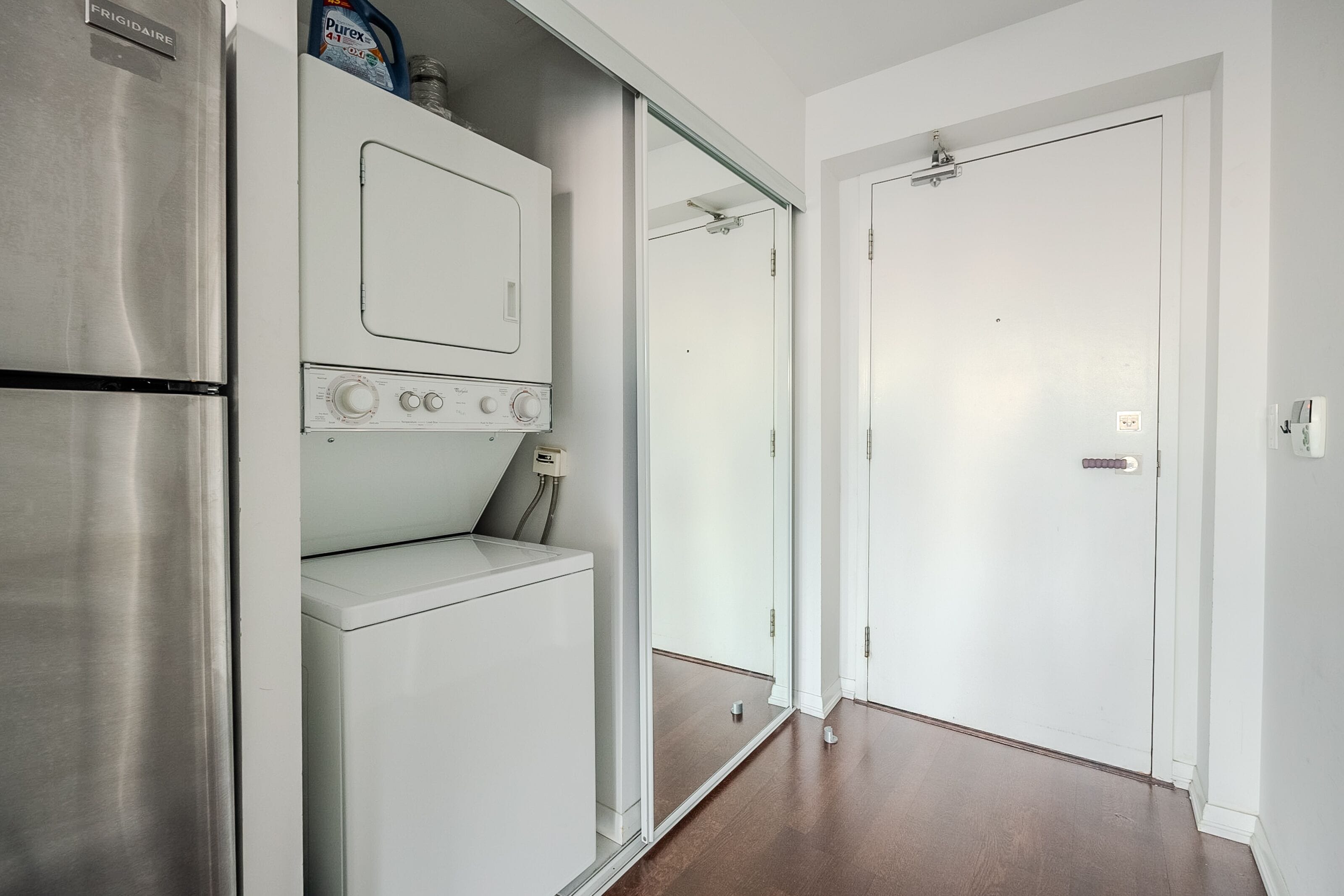 A compact kitchen with a stainless steel refrigerator, a built-in oven, and a microwave.