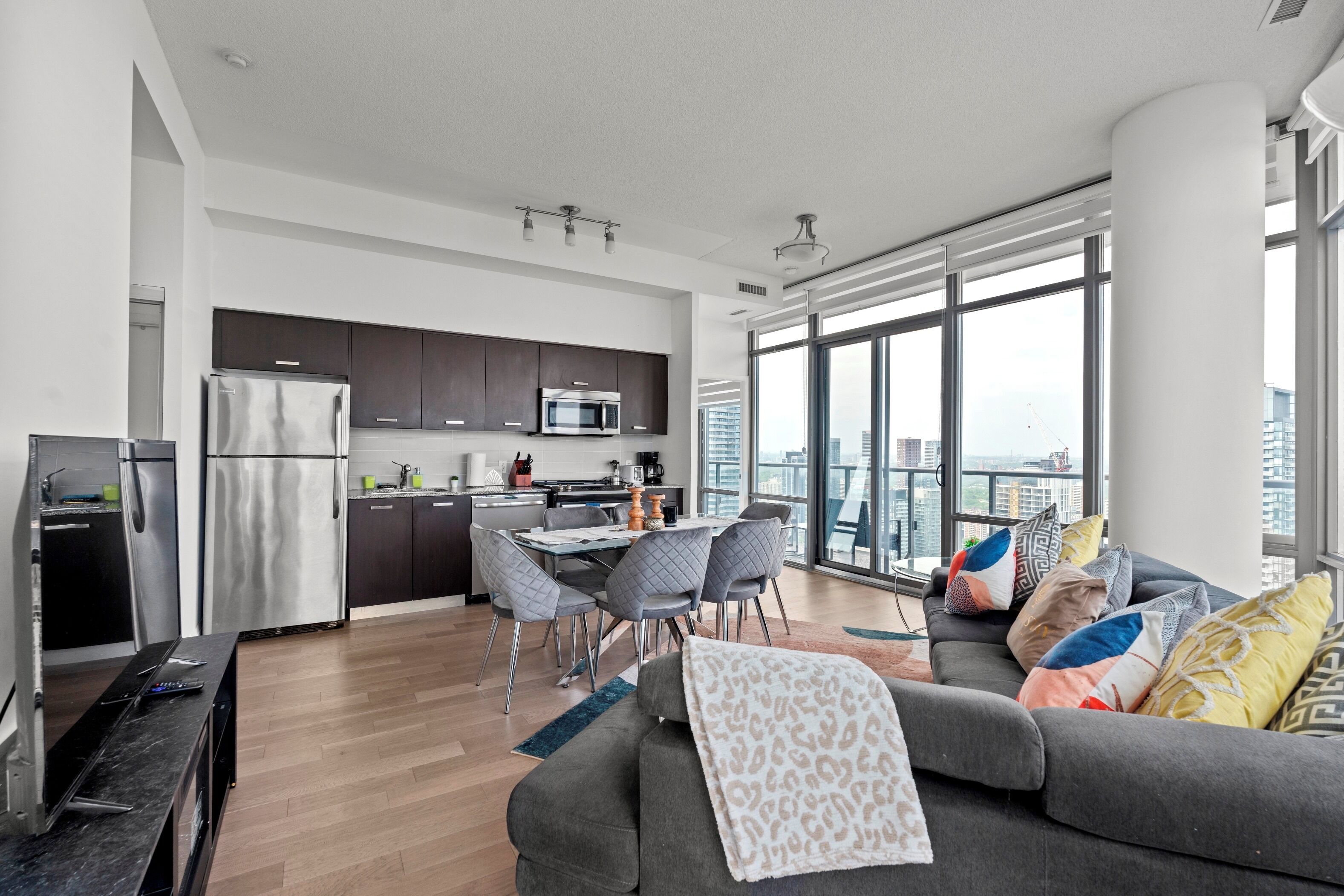A modern apartment with a kitchen, dining area, and living room with a large window.