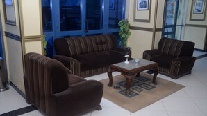 A living room with striped sofas, a coffee table, and a potted plant. - New Siesta Hotel  (Alexandria)