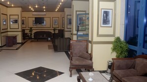 A lobby with a reception desk, seating area, and a large window. - New Siesta Hotel  (Alexandria)