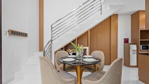 A modern dining area with a glass table, four chairs, and a staircase leading to another level. - Asasta Villa by Betterplace (Tabanan)