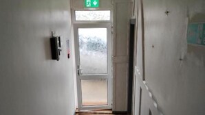 Ein Flur mit Holzboden, einer Tür mit Frostglas und einem grünen Feuerschutzschild.