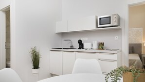 Una cocina moderna con armarios blancos, un microondas y una cafetera.