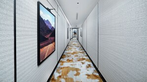 Un pasillo largo y estrecho con paredes blancas y texturizadas, y una alfombra estampada.