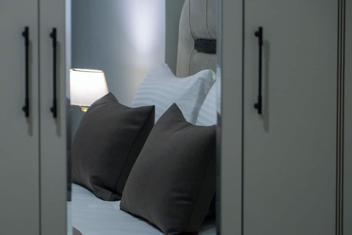 A bedroom with a bed, pillows, a nightstand, and a lamp.