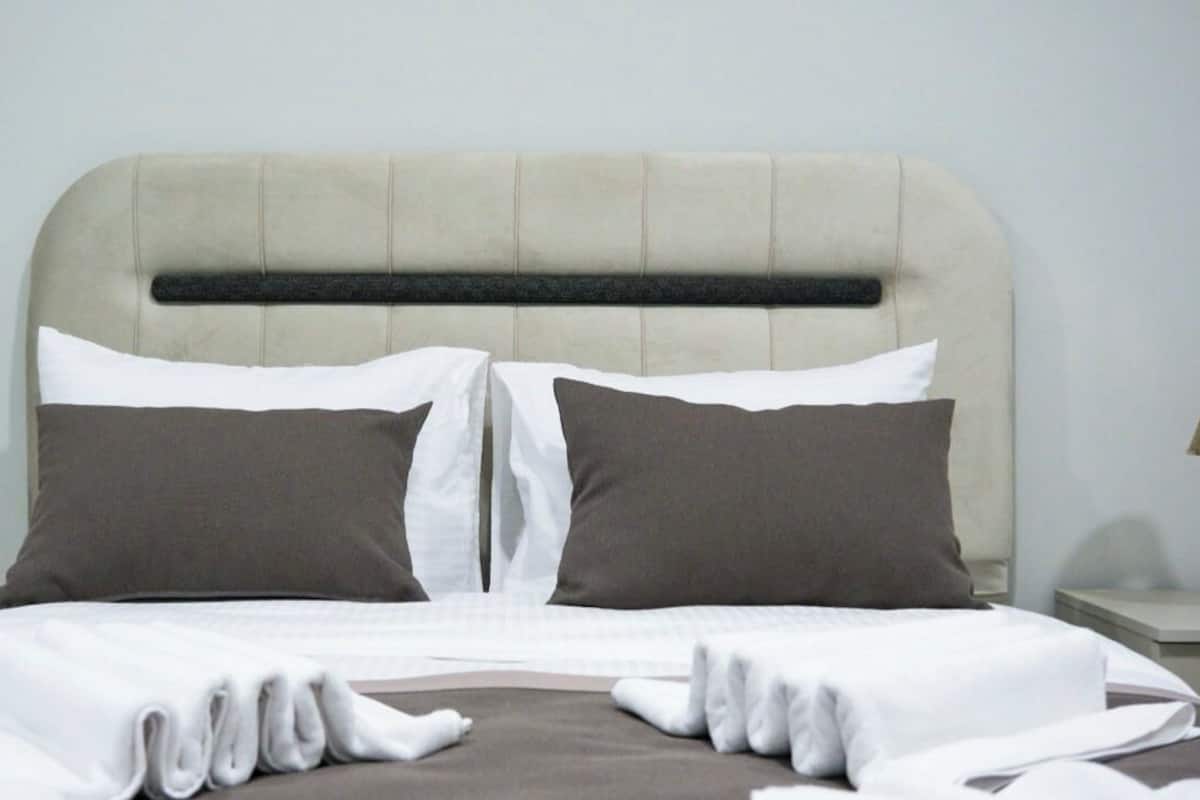 A neatly made bed with a headboard, two pillows, and a folded white blanket.