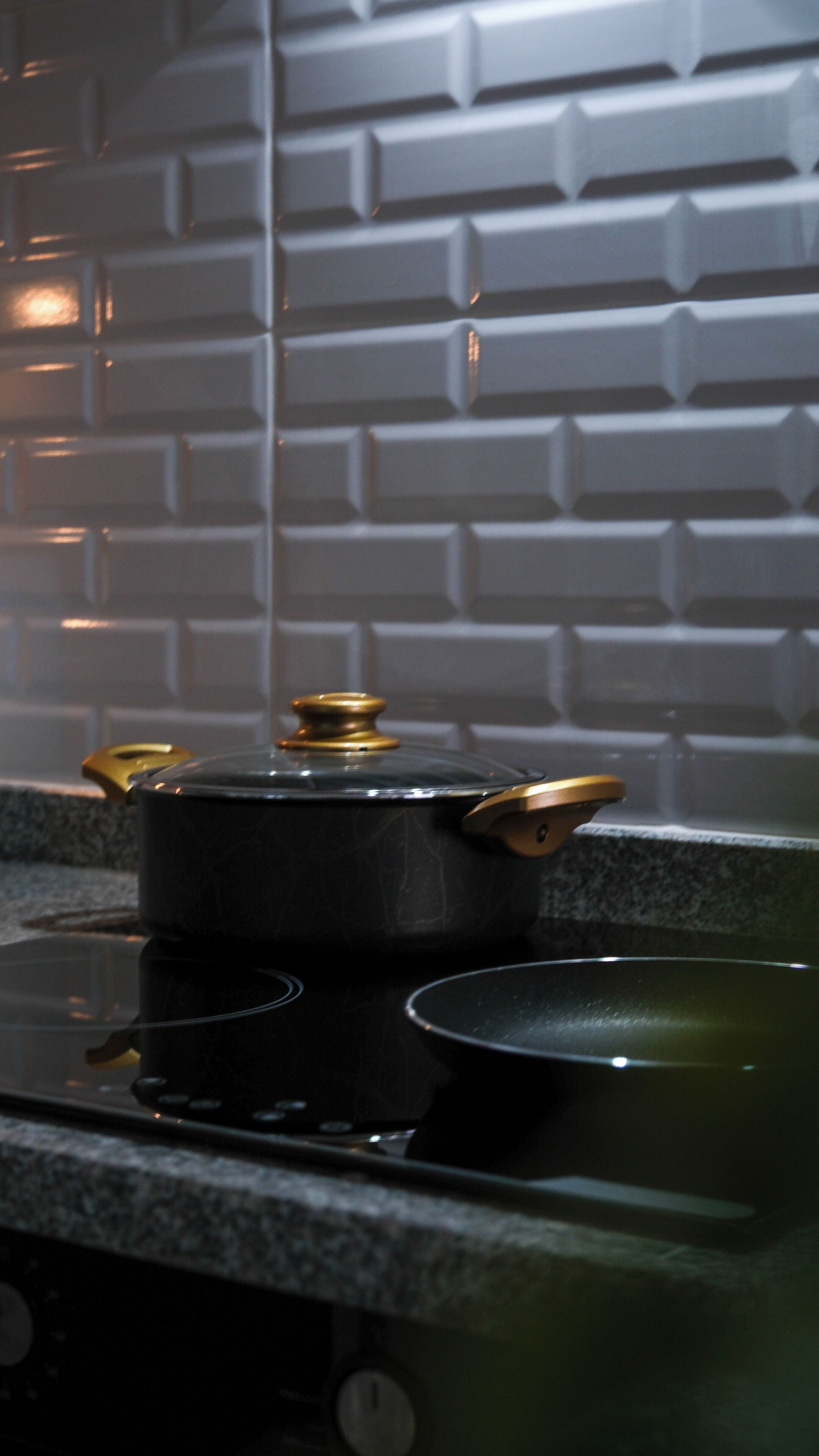 Une cuisine avec un poêle noir, une casserole dessus et un pare-feu décoré d’un motif en briques.