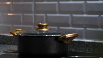 Une cuisine avec un poêle noir, une casserole dessus et un pare-feu décoré d’un motif en briques.