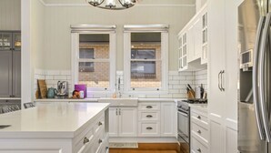 A modern kitchen with white cabinets, a stainless steel refrigerator, and a large island.