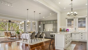 A spacious kitchen with white cabinetry, a large island, and a dining area with a view of the outdoors.