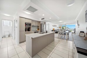 A modern kitchen with a central island, built-in appliances, and a view to the outside.