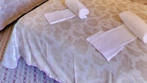 Habitación de hotel con dos camas, una mesita de noche, un cuadro con una escena de playa y una lámpara en el techo.
