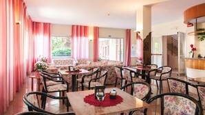 Un área de comedor con tapicería floral, una mesa de recepción y vistas al exterior.