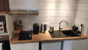 Eine moderne Küche mit zwei schwarzen Spülen, einer Edelstahl-Dunstabzugshaube und einer Holz Arbeitsplatte.