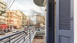 A balcony with a view of a busy street, a railing, and a door. - Margarita by halu! 3-BD tropical house (Thessaloniki)