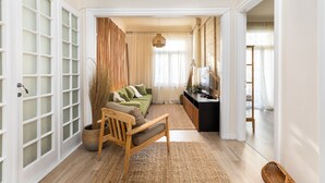 A living room with a sofa, a wooden chair, a woven basket, and a television. - Margarita by halu! 3-BD tropical house (Thessaloniki)