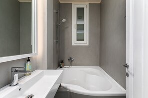 City-Apartment | Badezimmer | Badewanne, Designer-Toilettenartikel, Hausschuhe, Handtücher