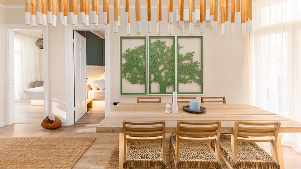 A dining area with a wooden table, woven chairs, and a hanging light fixture. - Margarita by halu! 3-BD tropical house (Thessaloniki)