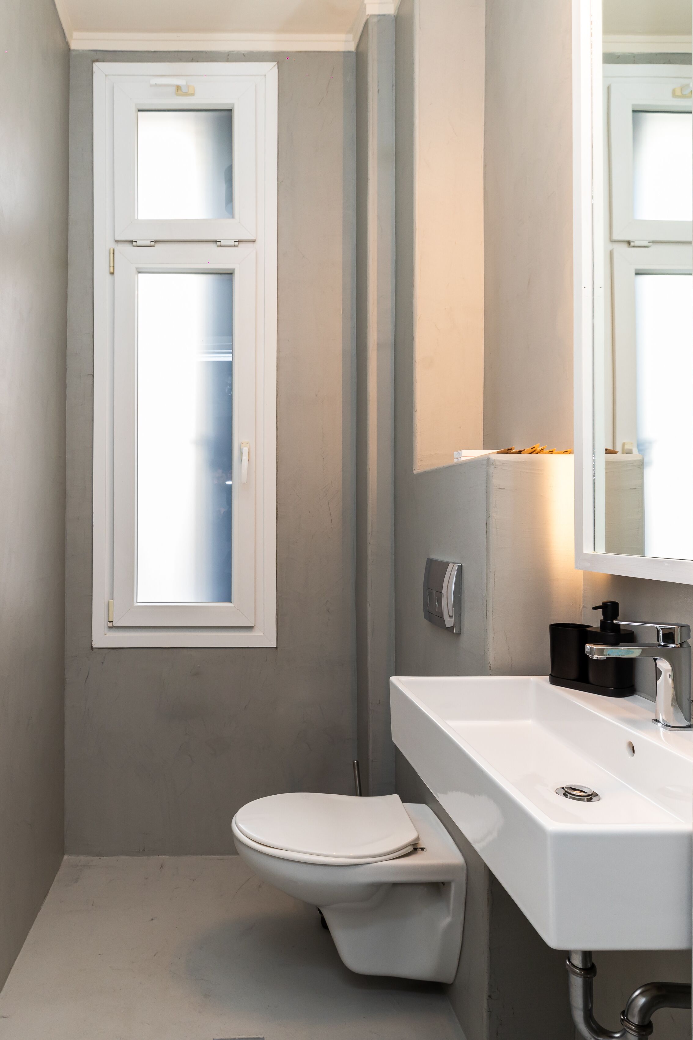 A small bathroom with a white toilet, a white sink, and a mirror above the sink.