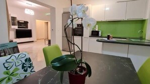 A modern kitchen with white cabinets, a green countertop, and a dining area with a black table and chairs.