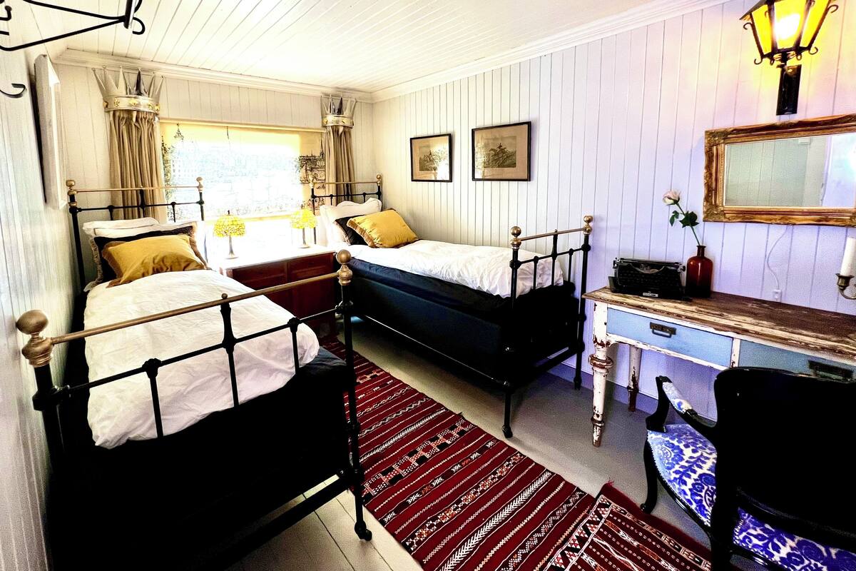 A room with two beds, a desk, a chair, a lamp, and a mirror.