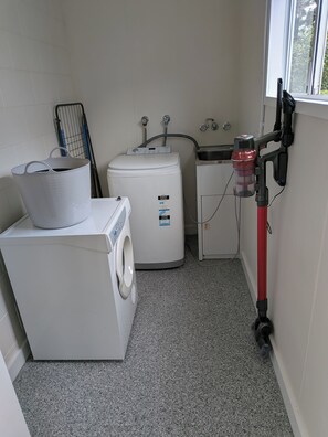 Ein Waschraum mit Waschmaschine, Trockner, Warmwasserbereiter und Schlauch.