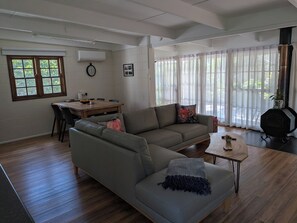A living room with a sofa, coffee table, and dining area. - Studio - self-contained (Reesville)