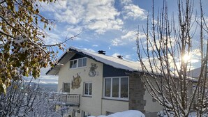 Ein zweistöckiges Gebäude mit verschneitem Dach und Wandgemälde an der Seite.