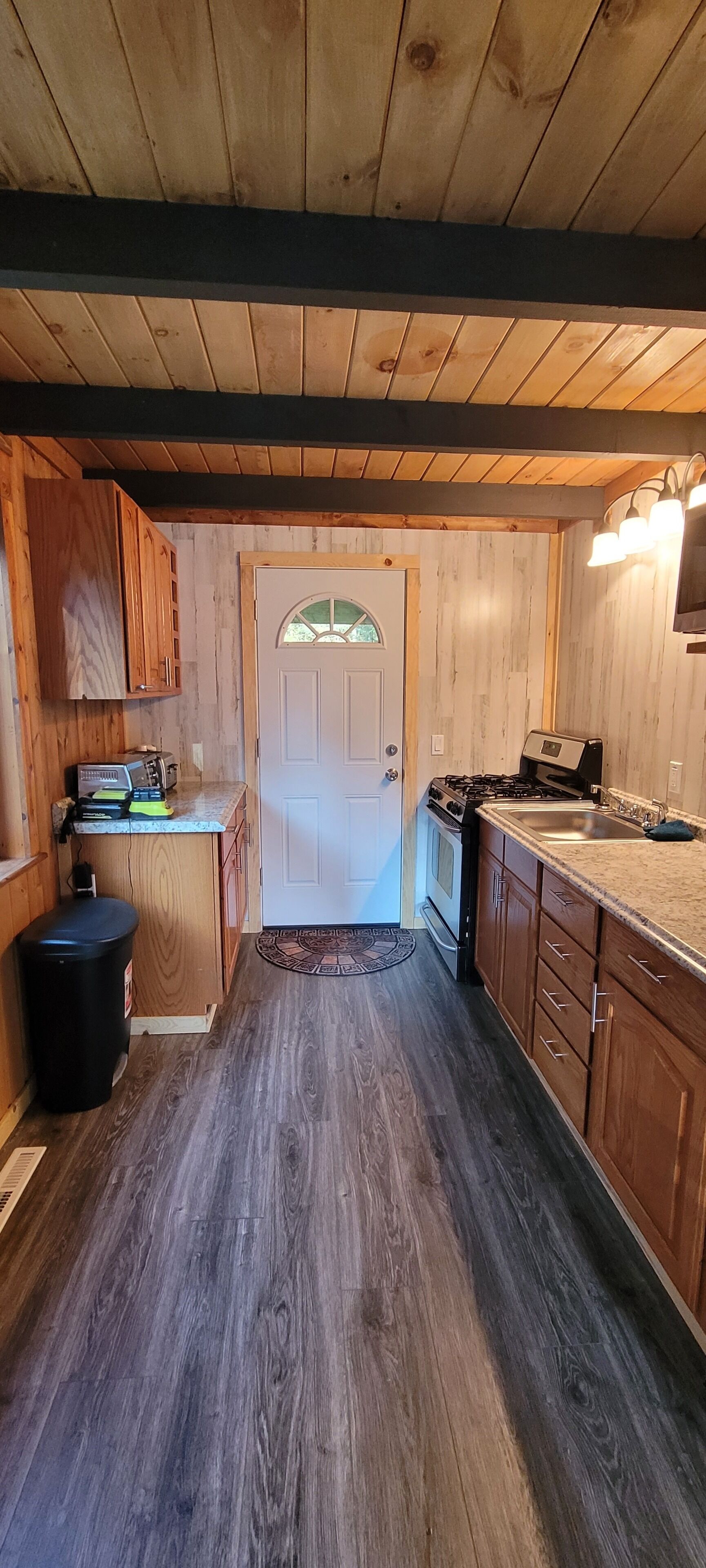 A kitchen with wooden cabinets, a stove, and a sink.