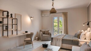 A modern bedroom with a bed, a desk, a chair, and a window with curtains. - Rosilion Studios & Apartments (Kefalonia)