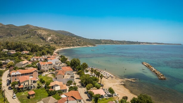 Un pueblo costero con edificios residenciales, una playa y barcos en el agua.