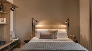 Un dormitorio ordenado con cama, lámparas de noche, mesita de noche y estante con libros y objetos decorativos.