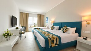 Habitación de hotel con una cama grande, un escritorio, una silla y un televisor.