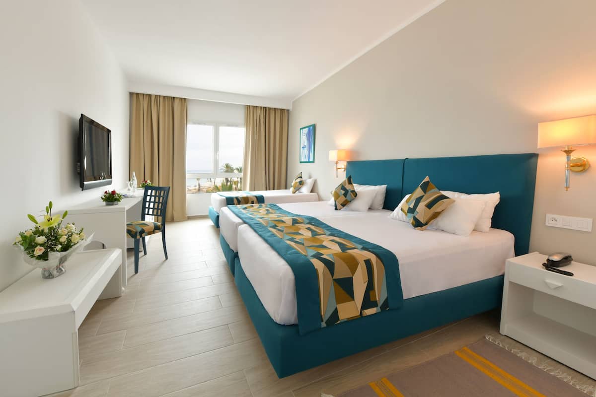A hotel room with a large bed, a desk, a chair, and a TV.