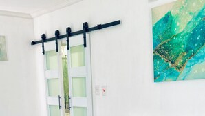 Ein Hotelzimmer mit Bett, einem Badezimmer mit Milchglasfenstern und einem Gemälde an der Wand.