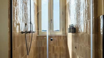 Un baño moderno con cabina de ducha de vidrio, paredes cubiertas de azulejos y vistas por la ventana de arco.