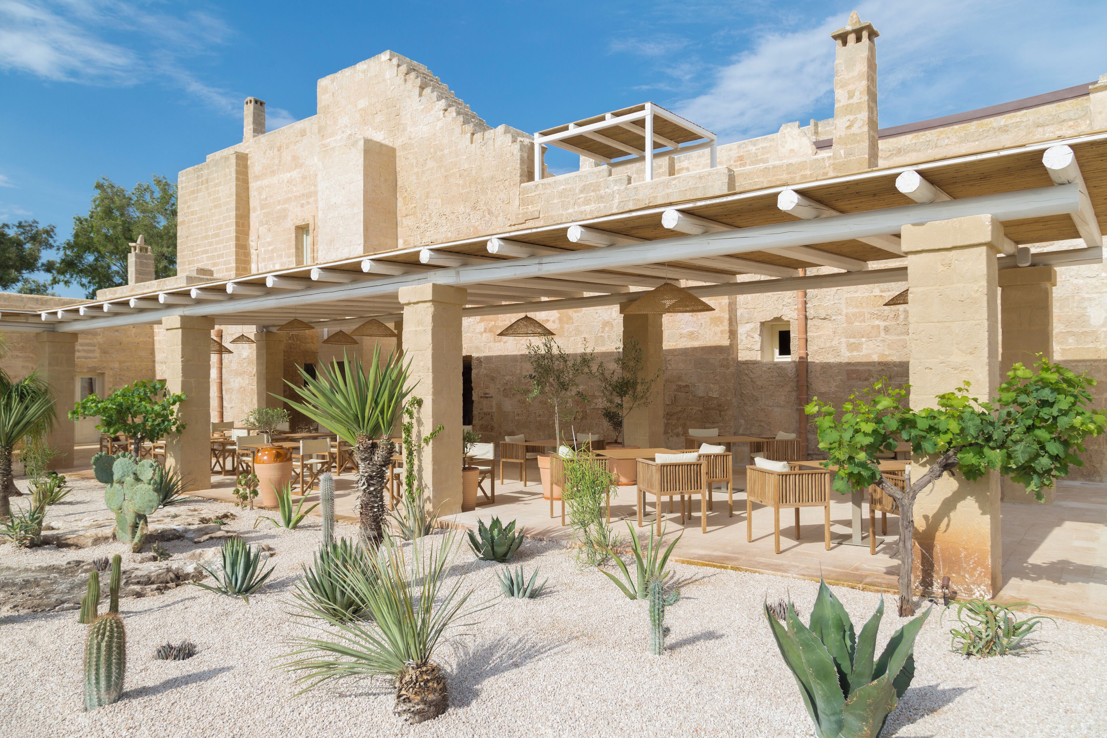 A courtyard with a pergola, seating area, and cacti.