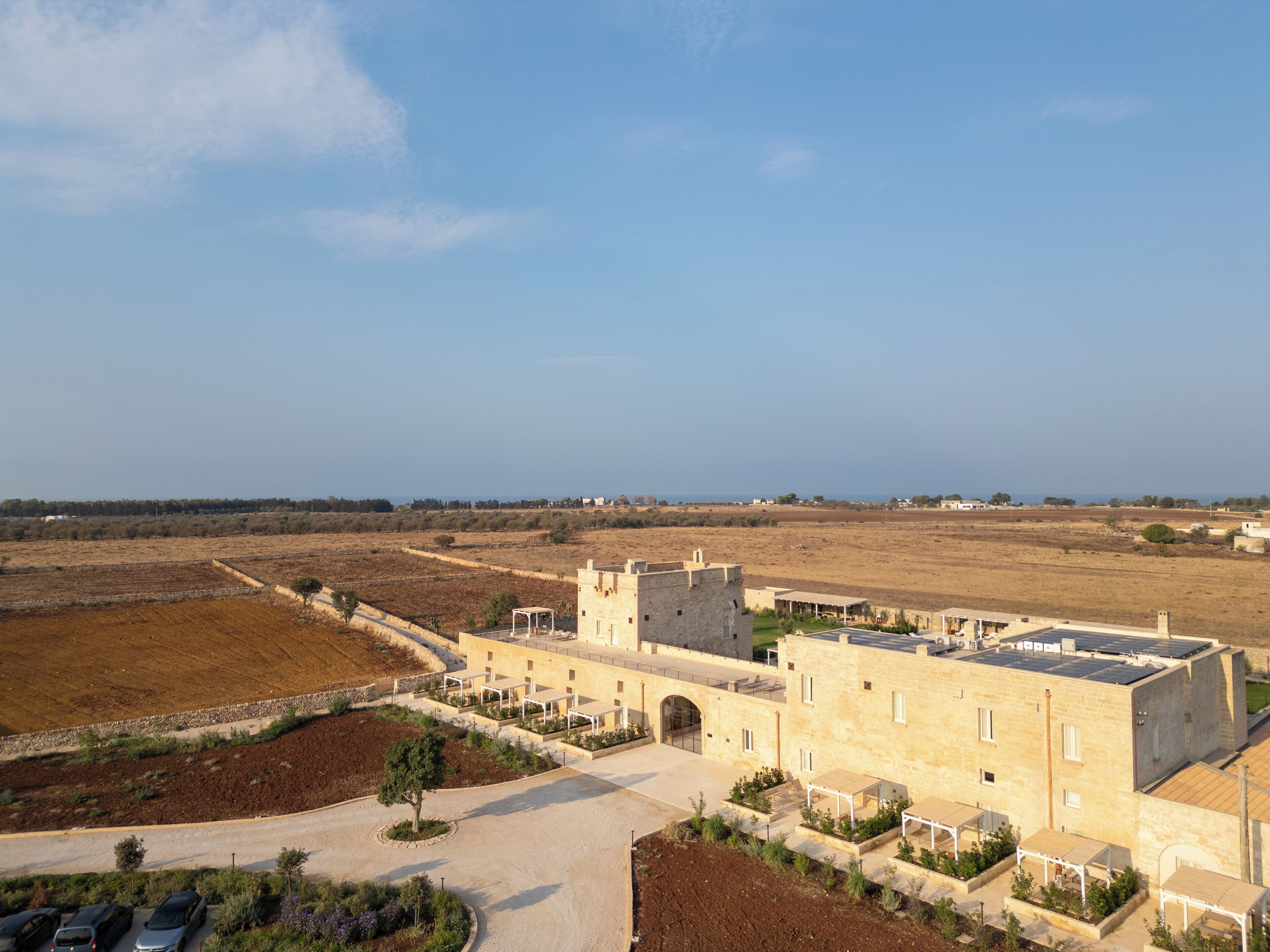 A castle-like building with a courtyard, surrounded by open fields and a clear sky.