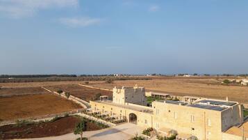 A castle-like building with a courtyard, surrounded by open fields and a clear sky.