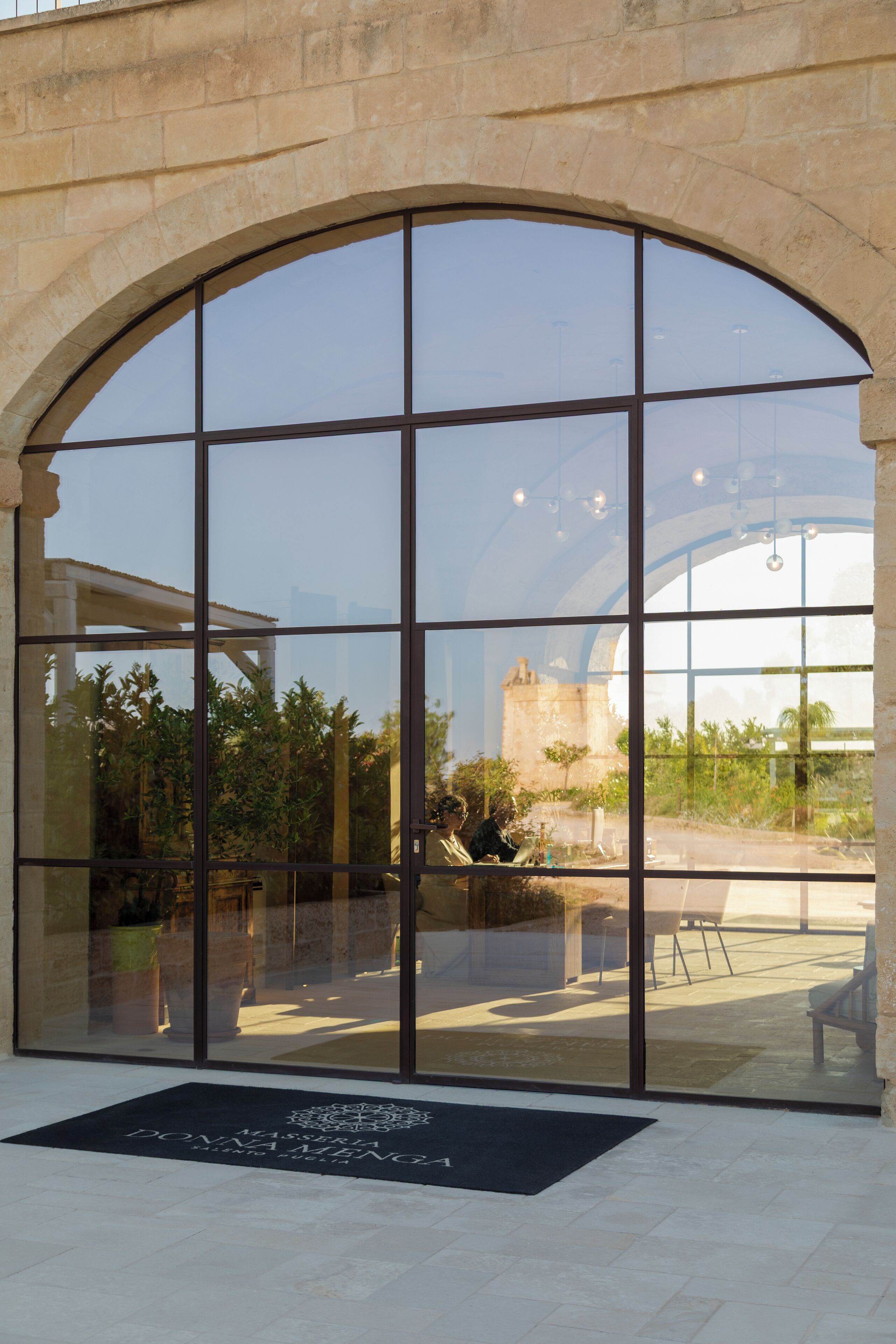 A large arched window with a view of outdoor seating and greenery.